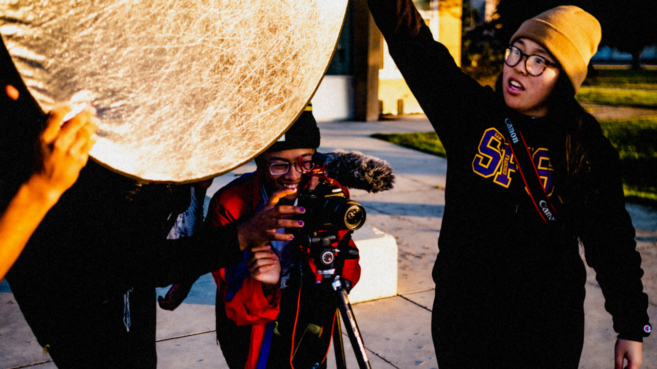 Crissy Field Center youth preparing a photoshoot. Crissy Field Center youth program participants working a photoshoot, holding a camera and light reflector.