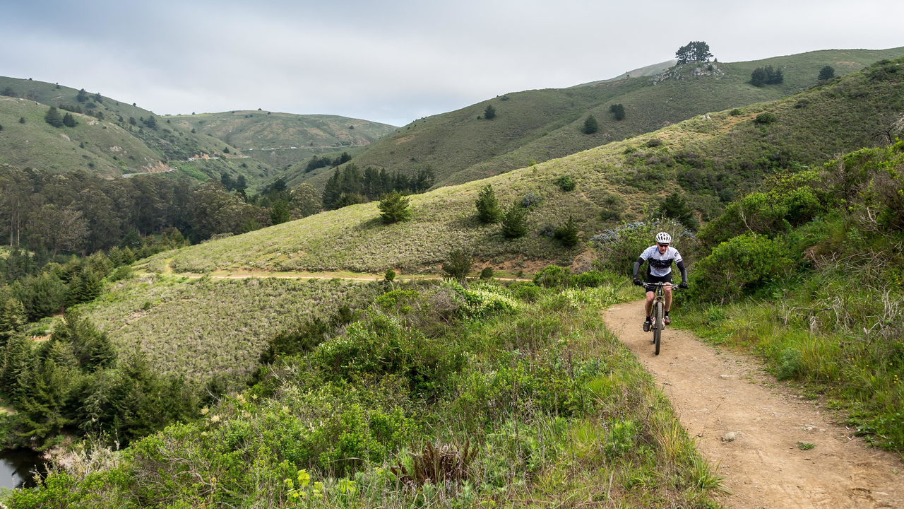 Cyclist pedals above Muir Beach Cyclist pedals above Muir Beach