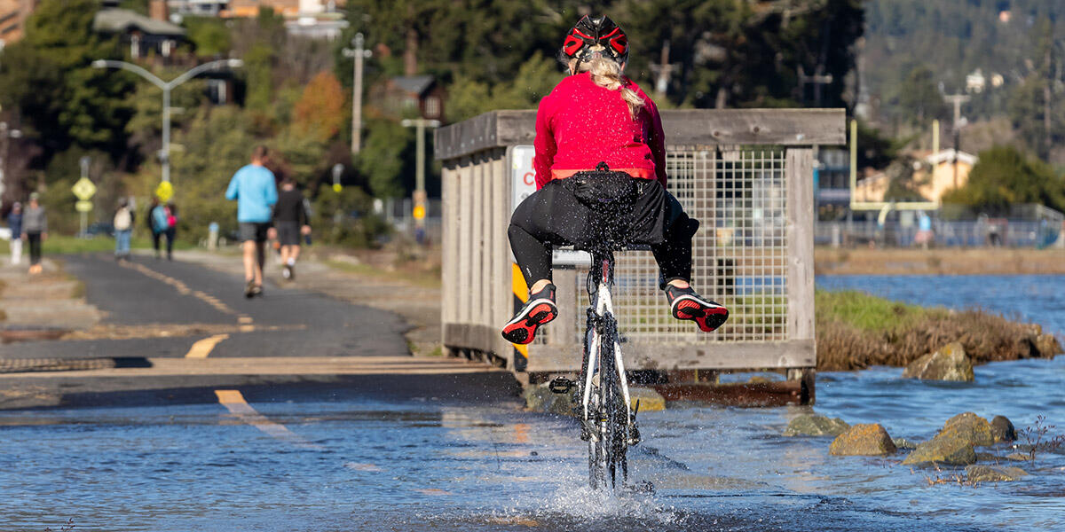 A bicyclist rides through water along a pedestrian path in Marin County.