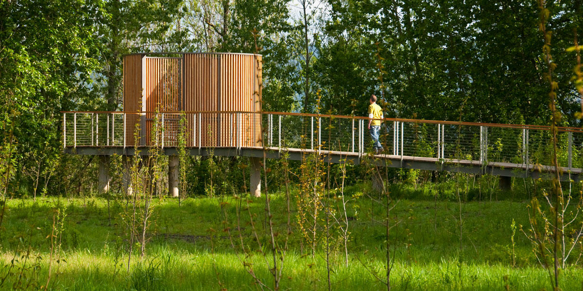 A person walks up a ramp toward an elliptical wooden structure