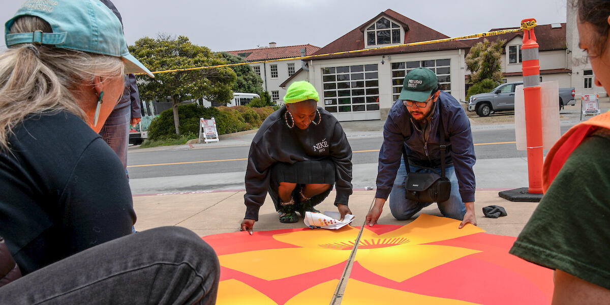 Artist and workers install adhesive artwork onto the sidewalks at Presidio Tunnel Tops