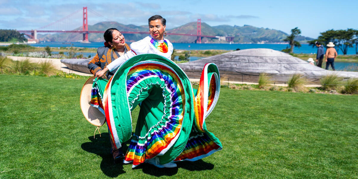 Two dancers performing at Presidio Tunnel Tops with a golden gate bridge view.