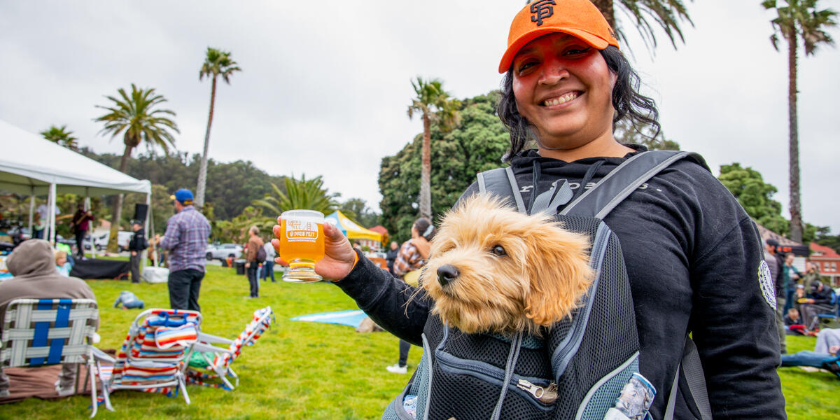 A woman poses with her dog at the Parks4All: Brewfest in the Presidio.