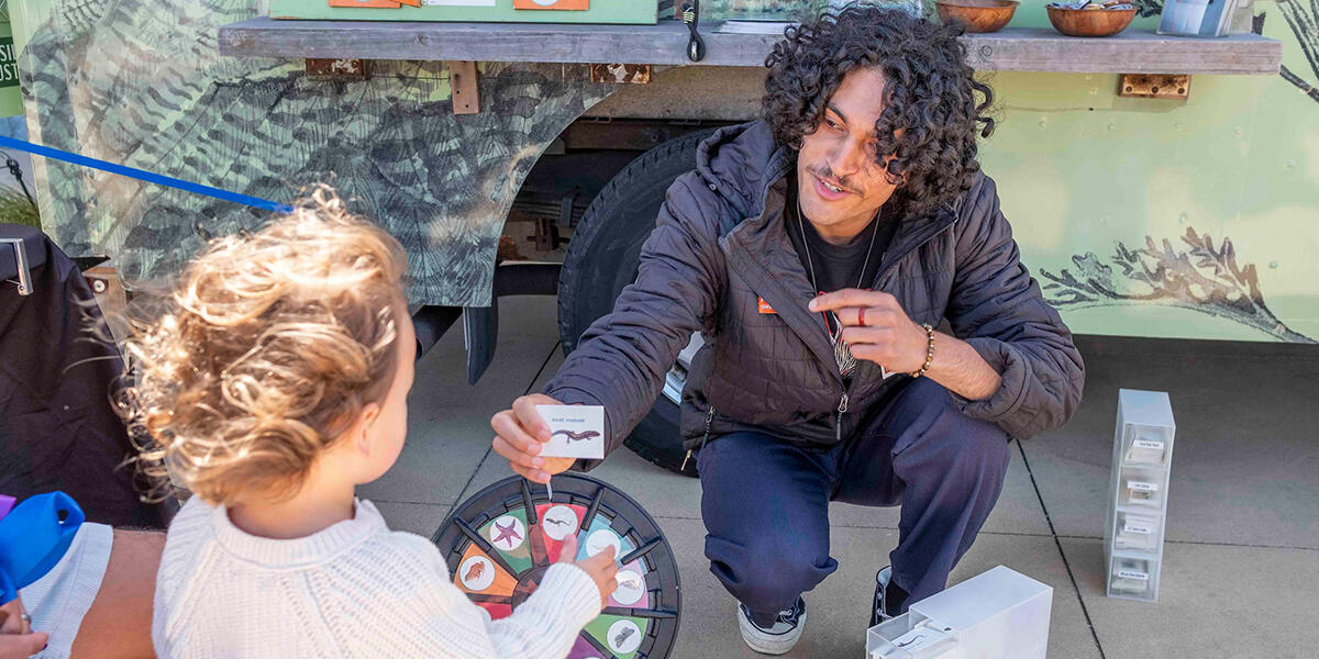 A young person visits the Roving Ranger, mobile trailhead, for stickers.