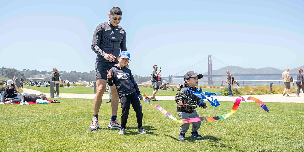 Posing for a photo at Pride in the Presidio at Presidio Tunnel Tops with the Golden Gate Bridge behind them.