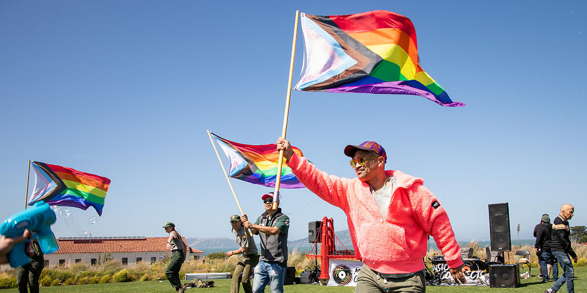 Revelers at the Pride in the Presidio event wave rainbow LGBTQ pride flag at the Presidio Tunnel Tops.