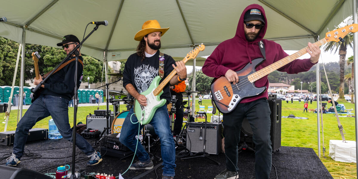 A band energetically performing on a stage in the Presidio during Parks4All: Brewfest 2024