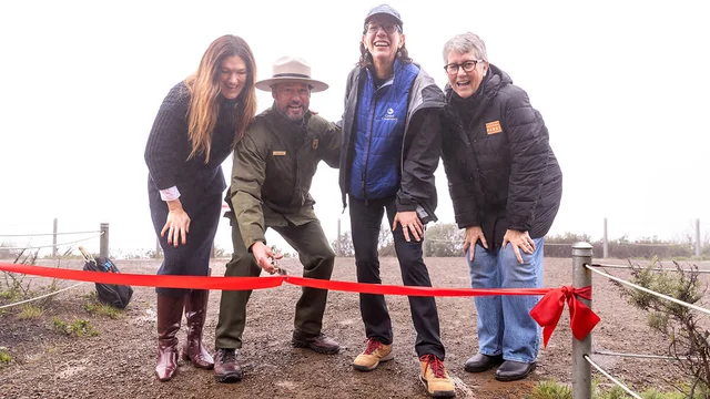 Four people at a ribbon-cutting event for the completion of the Hawk Hill Visito