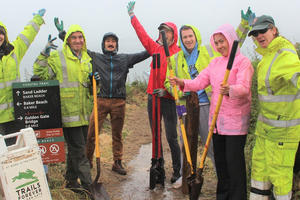 Volunteers in rain gear celebrate their hard work on the Coastal Trail.