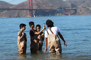 a small group of high school students learn to use environmental testing tools with an educator from the Crissy Field Center