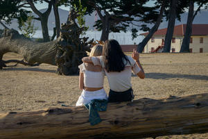Couple sits on felled tree looking towards the Golden Gate Bridge