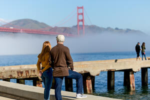 A couple stops to take in a Golden Gate Bridge view at Crissy Field East Beach