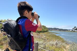 Kid with binoculars staring at Crissy Field Marsh.