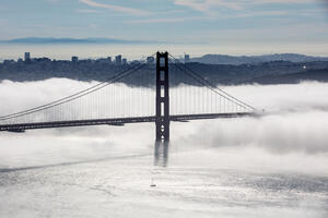 Golden Gate bridge in a layer of fog with a view of San Francisco behind it. 