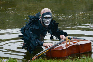 Musician Andy Meyerson wears an elaborate costume with a cello floating in Sutro Baths.