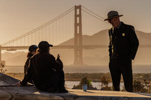 NPS ranger enjoying a conversation at the Presidio Tunnel Tops with the Golden Gate Bridge backdrop.