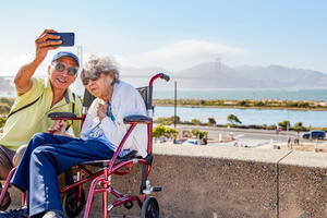 Elderly couple poses for a selfie before the Golden Gate Bridge at Presidio Tunnel Tops.