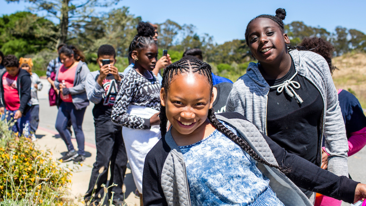 Camping at the Presidio participants on a hike. A youth group smiling as they hike through Presidio trails in San Francisco