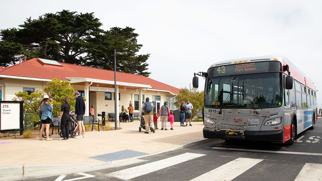 Take San Francisco Muni to Presidio Tunnel Tops A red and gray San Francisco Muni bus parked at a station in the Presidio