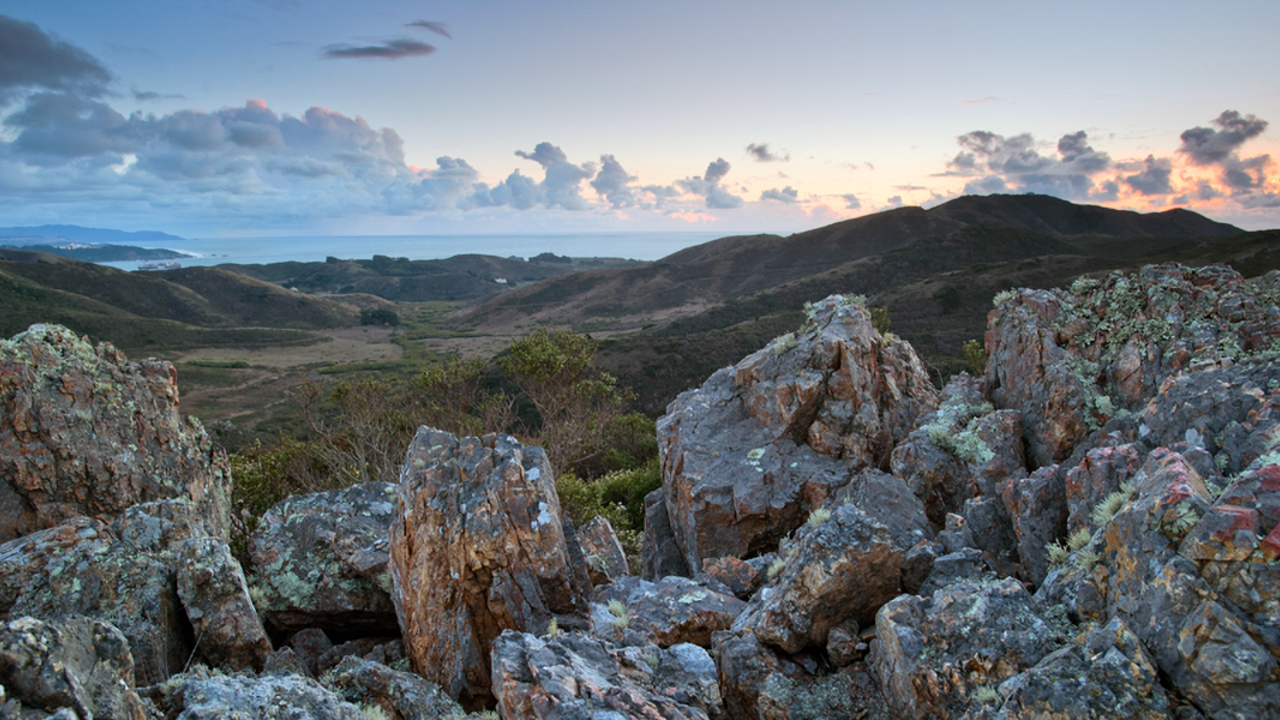 Gerbode Valley Scenic landscape view of Gerbode Valley in the Marin Headlands. Rocky boulders in the foreground frame the green expanse of the valley and mountains, and a pleasant sky with light clouds.