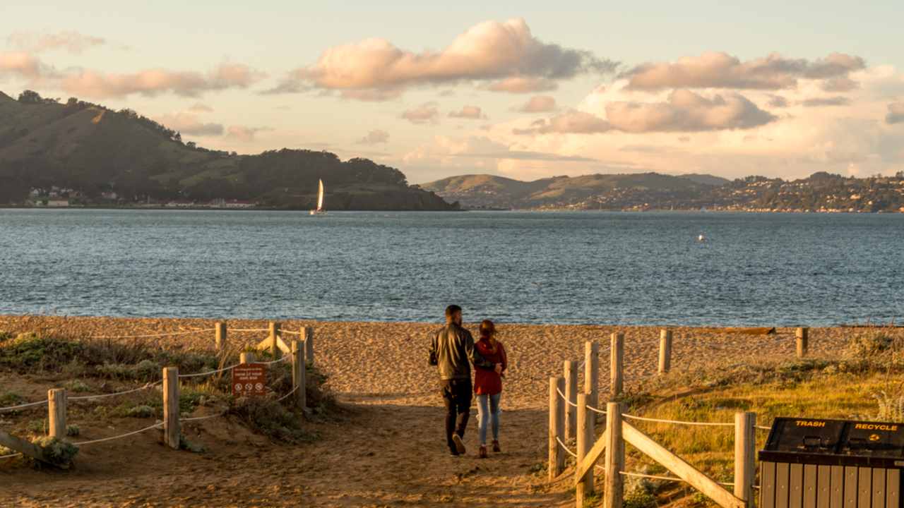 Crissy Field East Beach Visitors step out onto Crissy Field East Beach where the sunset casts warm light over the Golden Gate and San Francisco bay.