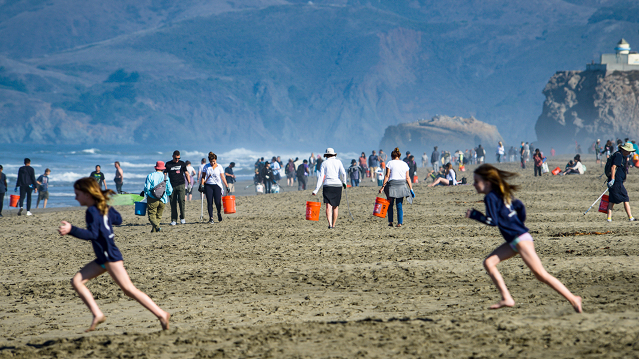 OCBE_20190921_RCW_18_2x1.jpg Two girls run in foreground of a wide shot of a crowded Ocean Beach.