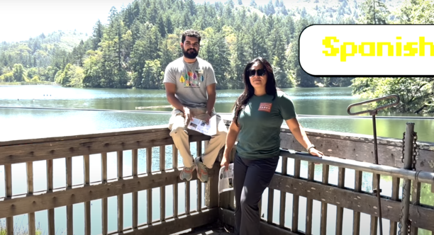 Parks Conservancy staff members take us on a self-guided forest walk in multiple languages. Parks Conservancy staff members sit on a fence in front of Lake Lagunitas, smiling at the camera. The title "SPANISH" is in the upper right.