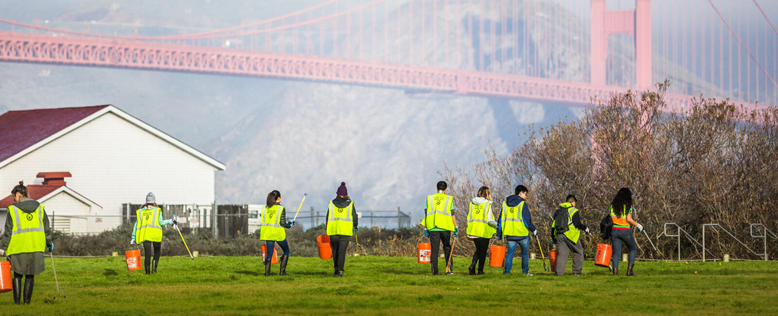 A group of volunteers in neon vests with the Golden Gate Bridge nearby