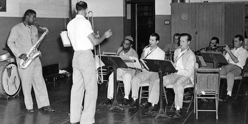 A historic black-and-white photograph of a group of incarcerated musicians at Alcatraz Island playing in a prison band. 