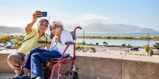 Elderly couple poses for a selfie before the Golden Gate Bridge at Presidio Tunnel Tops.