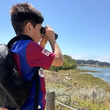 Kid with binoculars staring at Crissy Field Marsh.